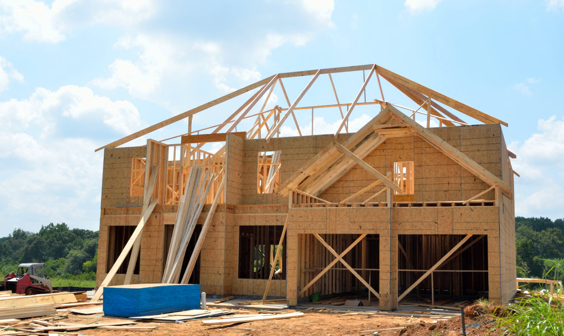 House under construction, wooden frame, blue sky, two-car garage, lumber, construction site.