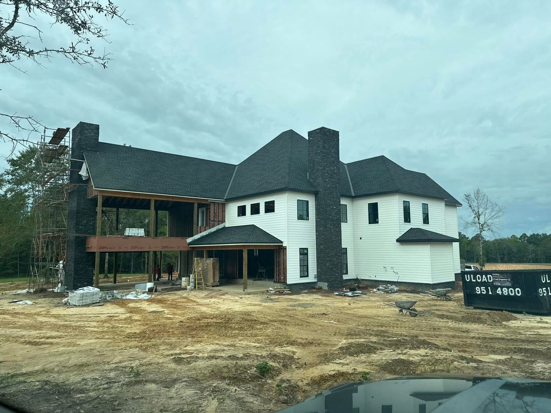 A large white house is being built in a dirt field.