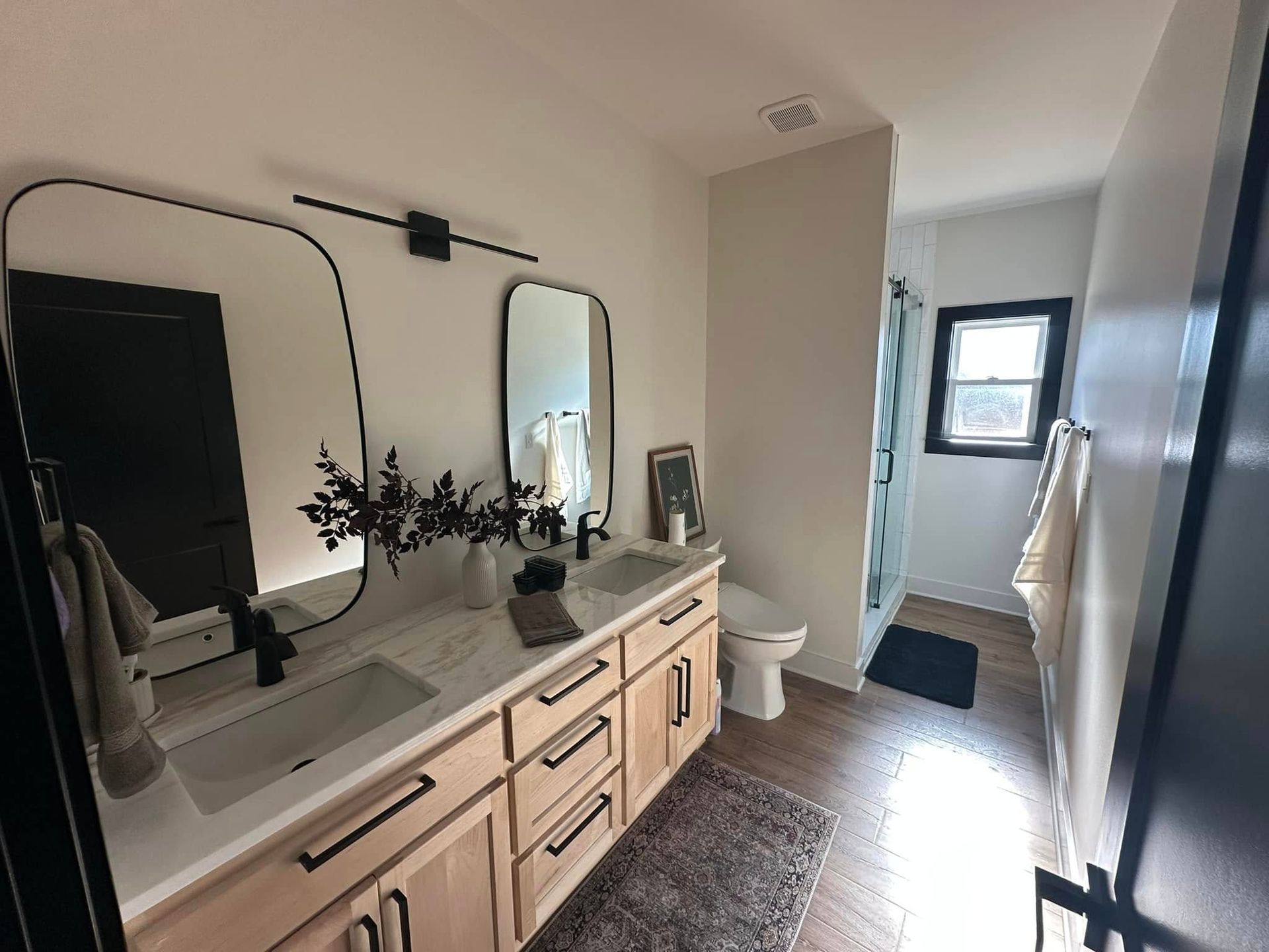 A bathroom with two sinks , a toilet , and a mirror.