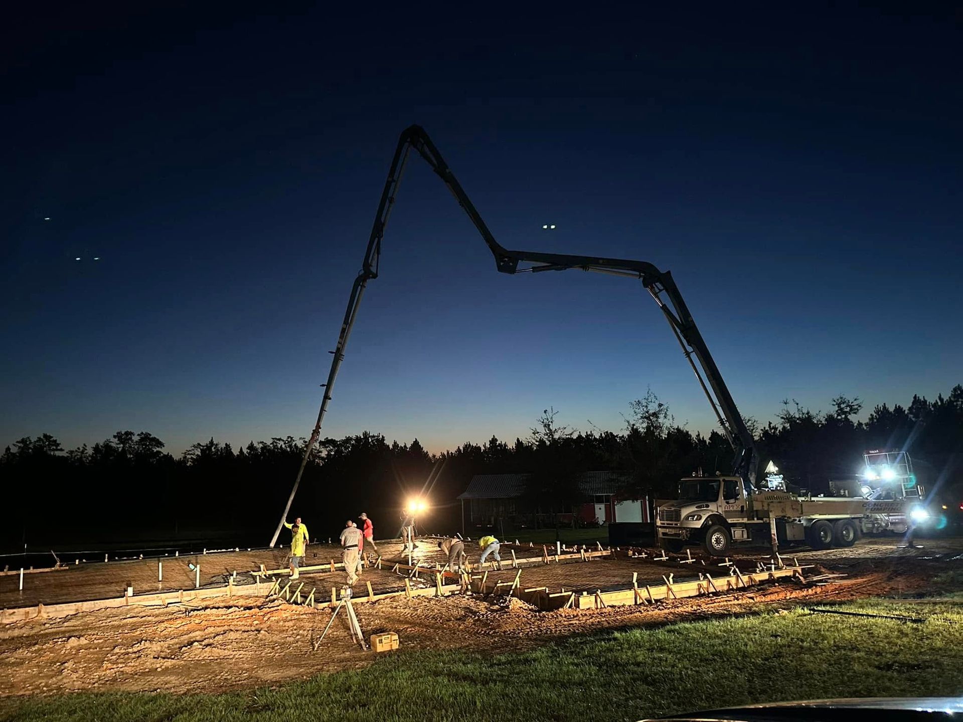 A concrete pump is being used to pour concrete at night