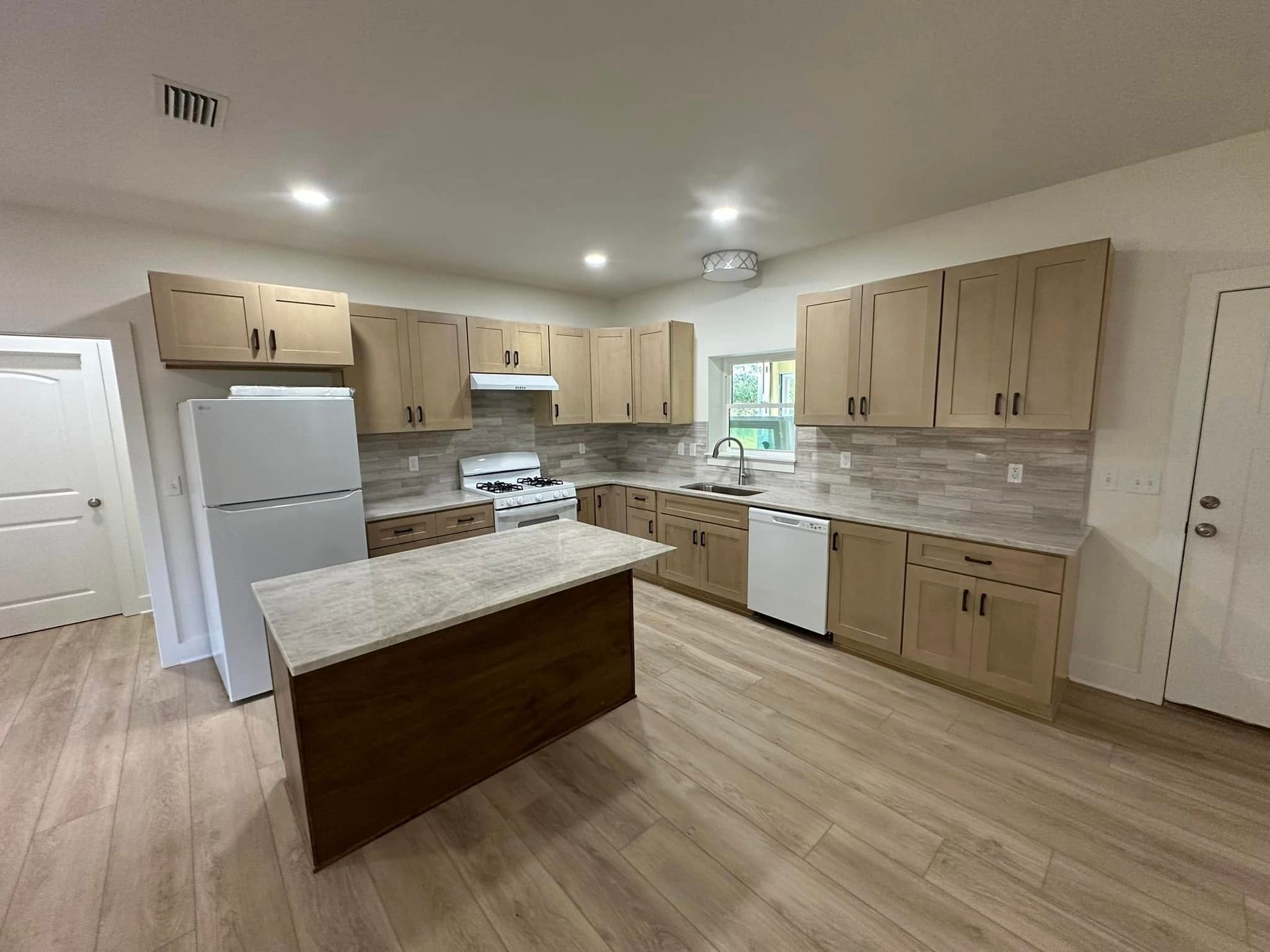 A kitchen with wooden cabinets and a large island in the middle.