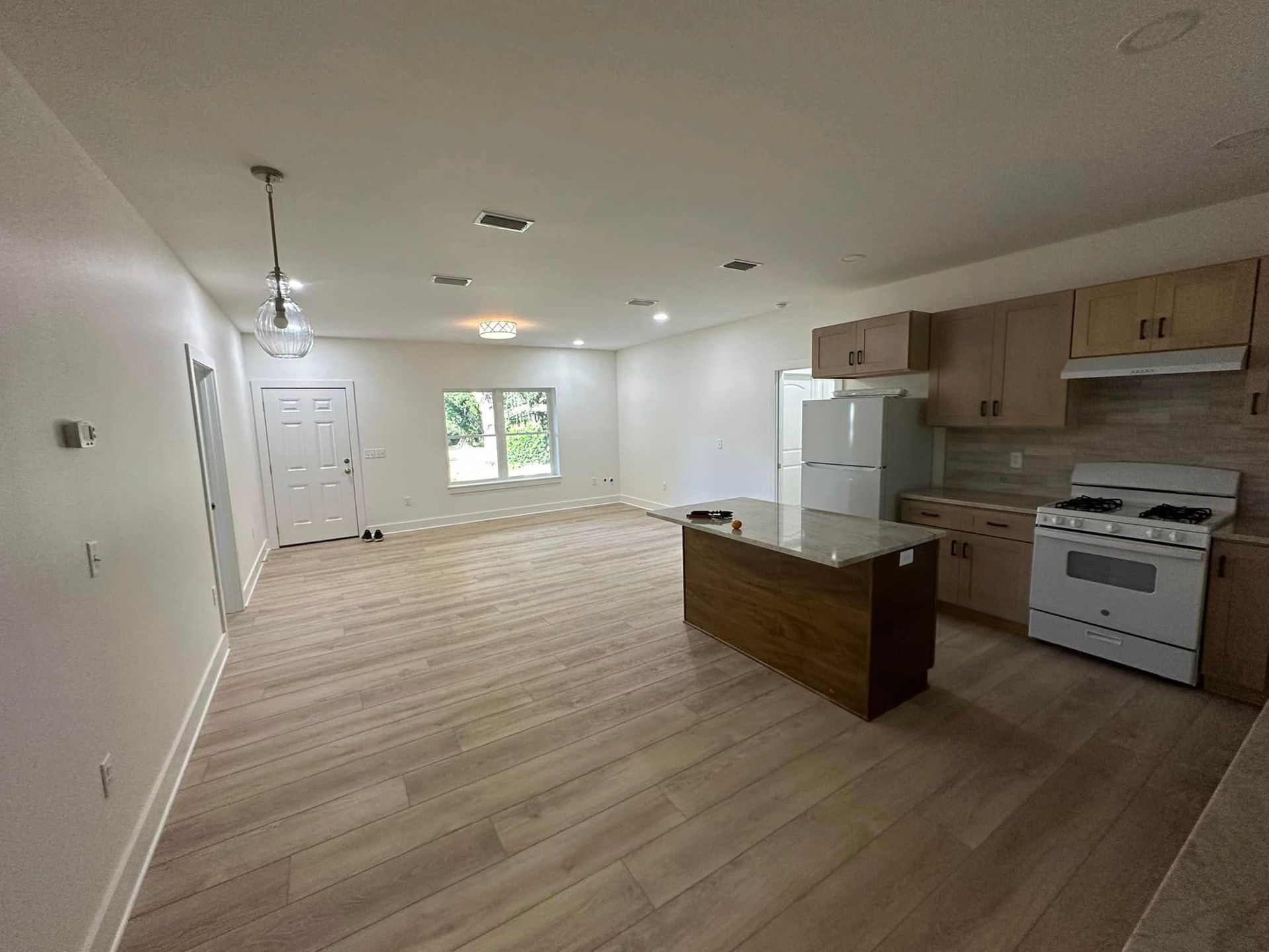 A kitchen with a stove , refrigerator , sink , and wooden cabinets.