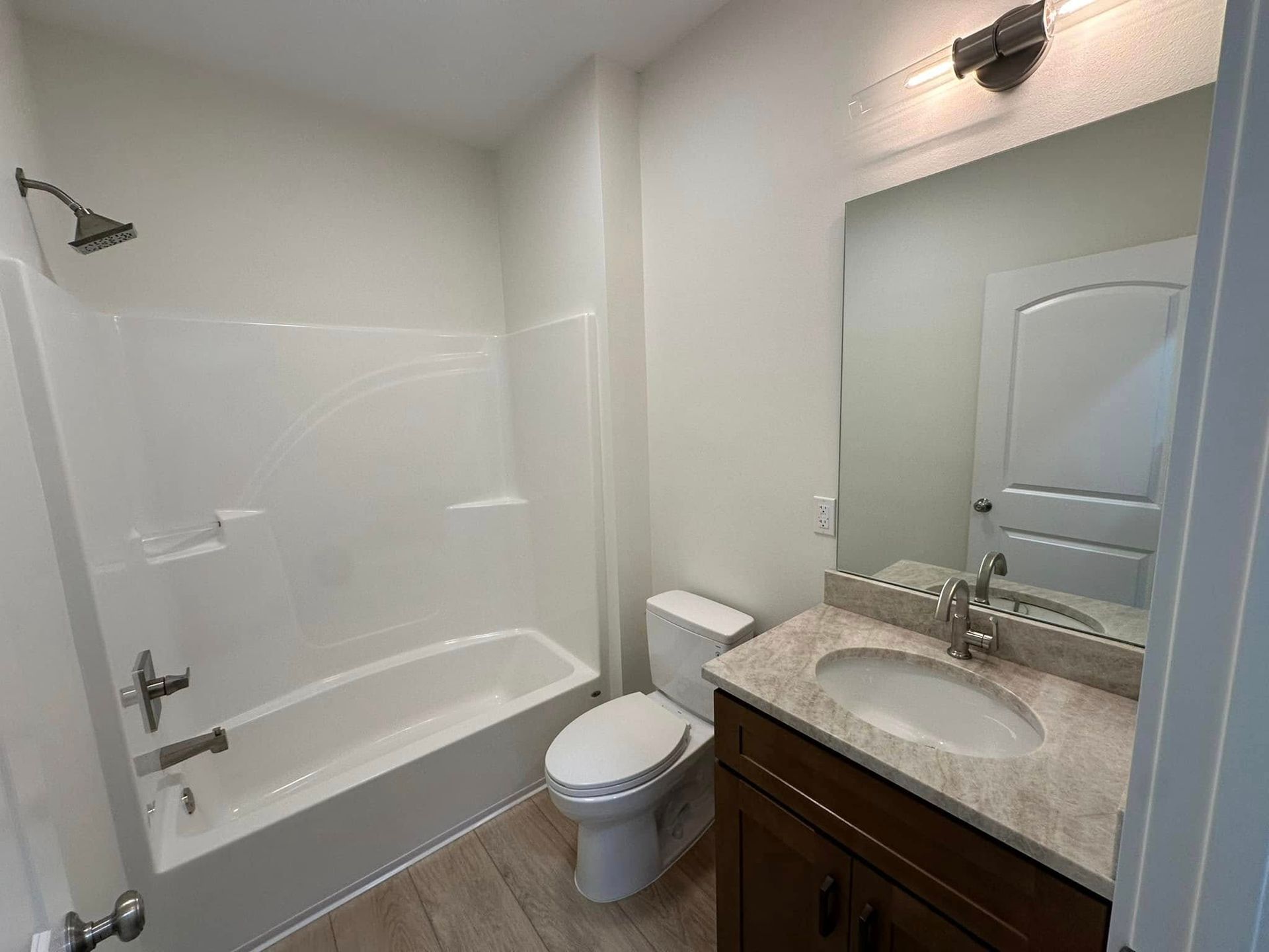 A bathroom with a toilet , sink , bathtub and mirror.