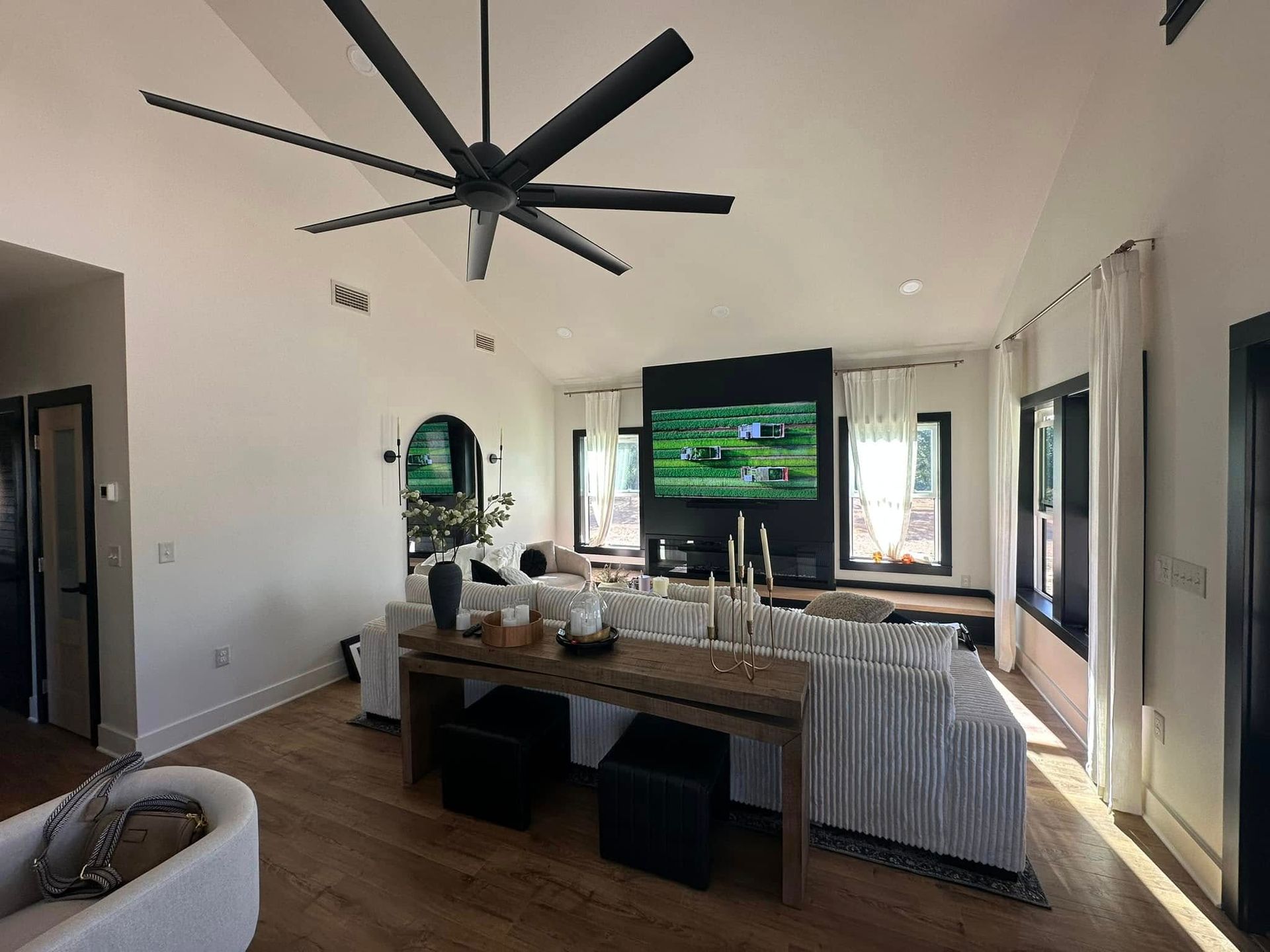 A living room with a ceiling fan and a flat screen tv.