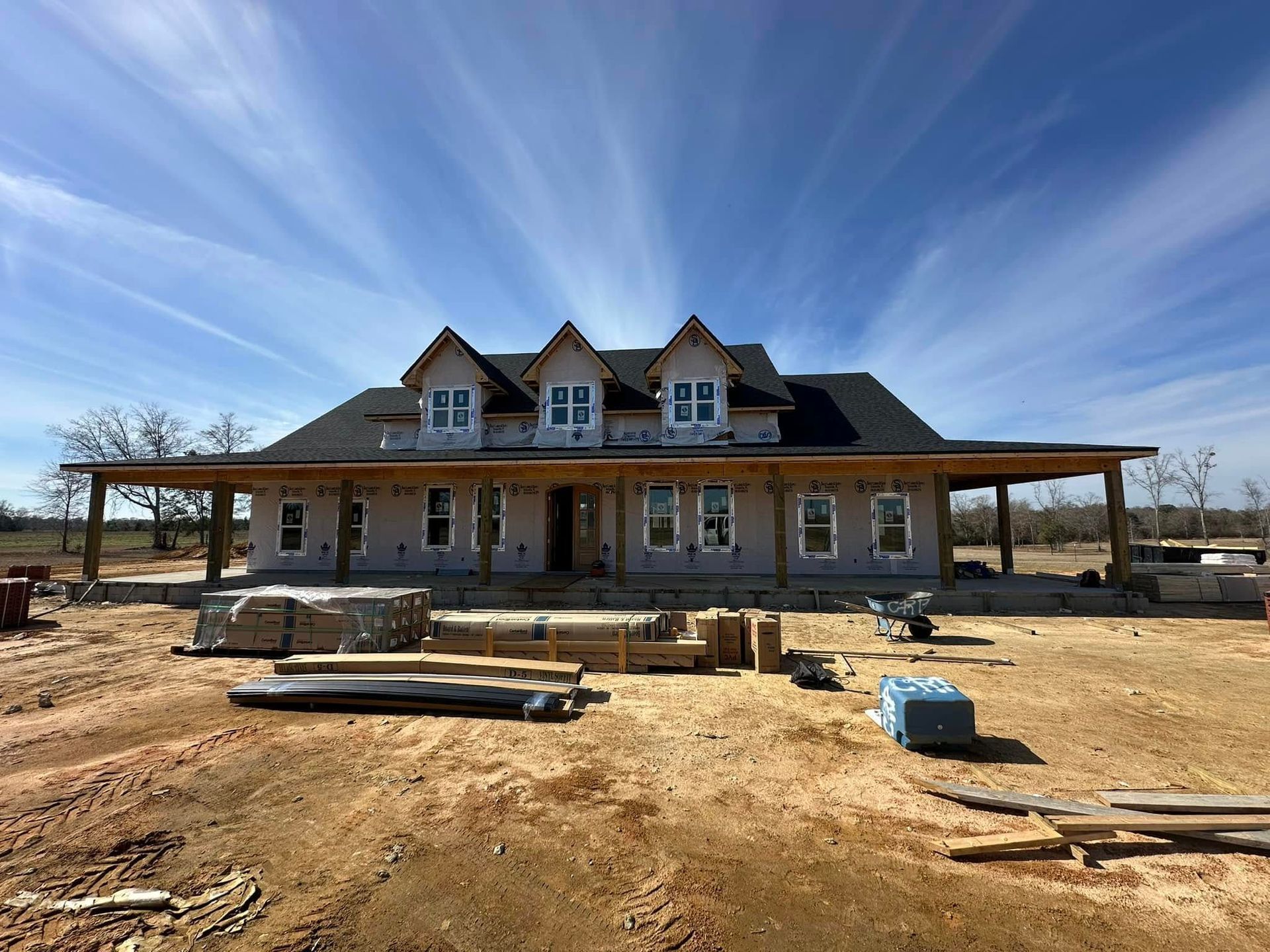 A large house is being built in a dirt field.