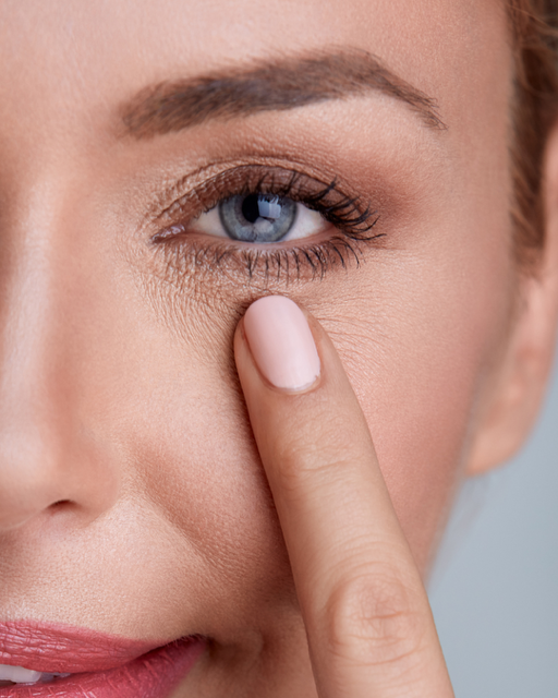 Frau im Bademantel betrachtet glanzlose Haut im Spiegel – Haut Glow zurückgewinnen