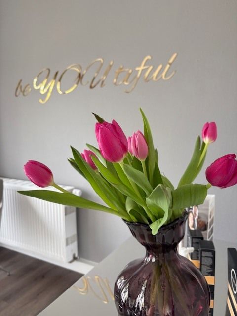 Frau im Bademantel betrachtet glanzlose Haut im Spiegel – Haut Glow zurückgewinnen