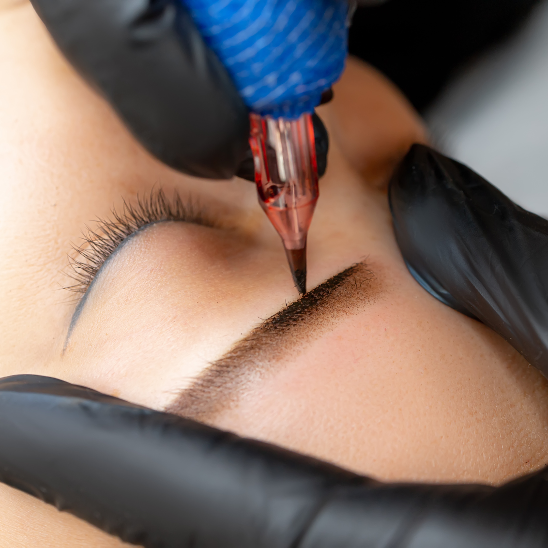 Eyebrow microblading: Technician's hands in black gloves, using a pen to tattoo pigment onto an eyebrow.