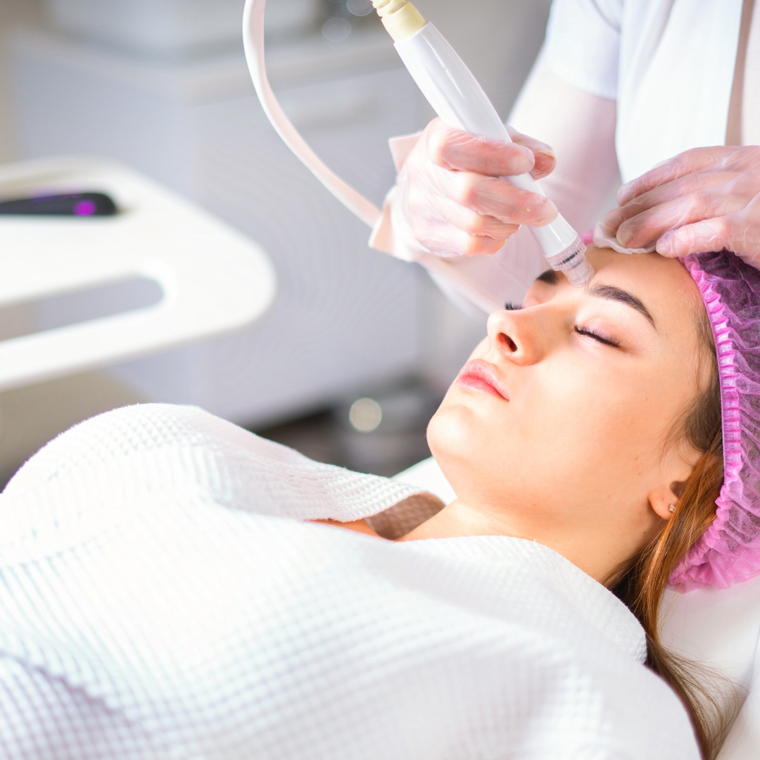 Woman receiving facial treatment in a clinic; a medical professional holds a device to the woman’s forehead.