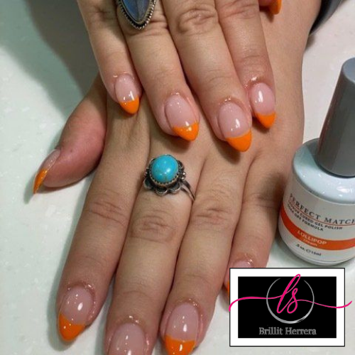 Hands with French manicure, orange tips, with rings. A bottle of nail polish is beside the hand.