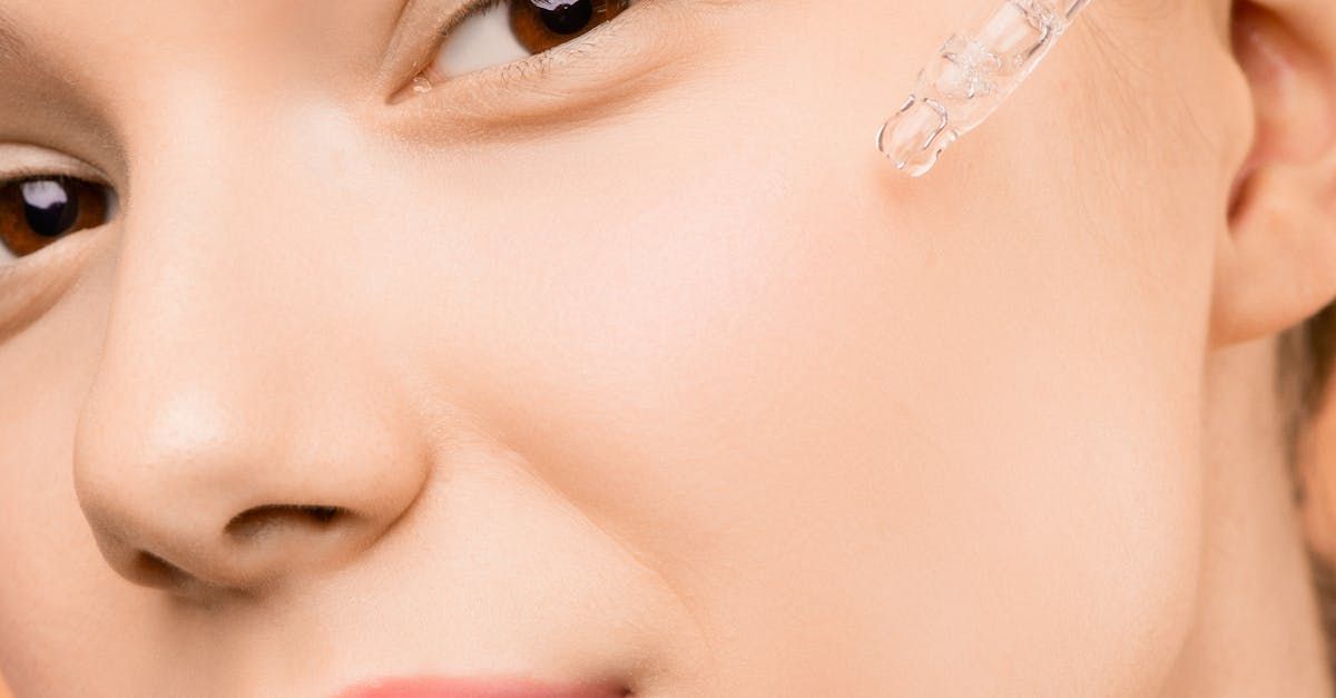 Close-up of person applying skincare serum with dropper to cheek.
