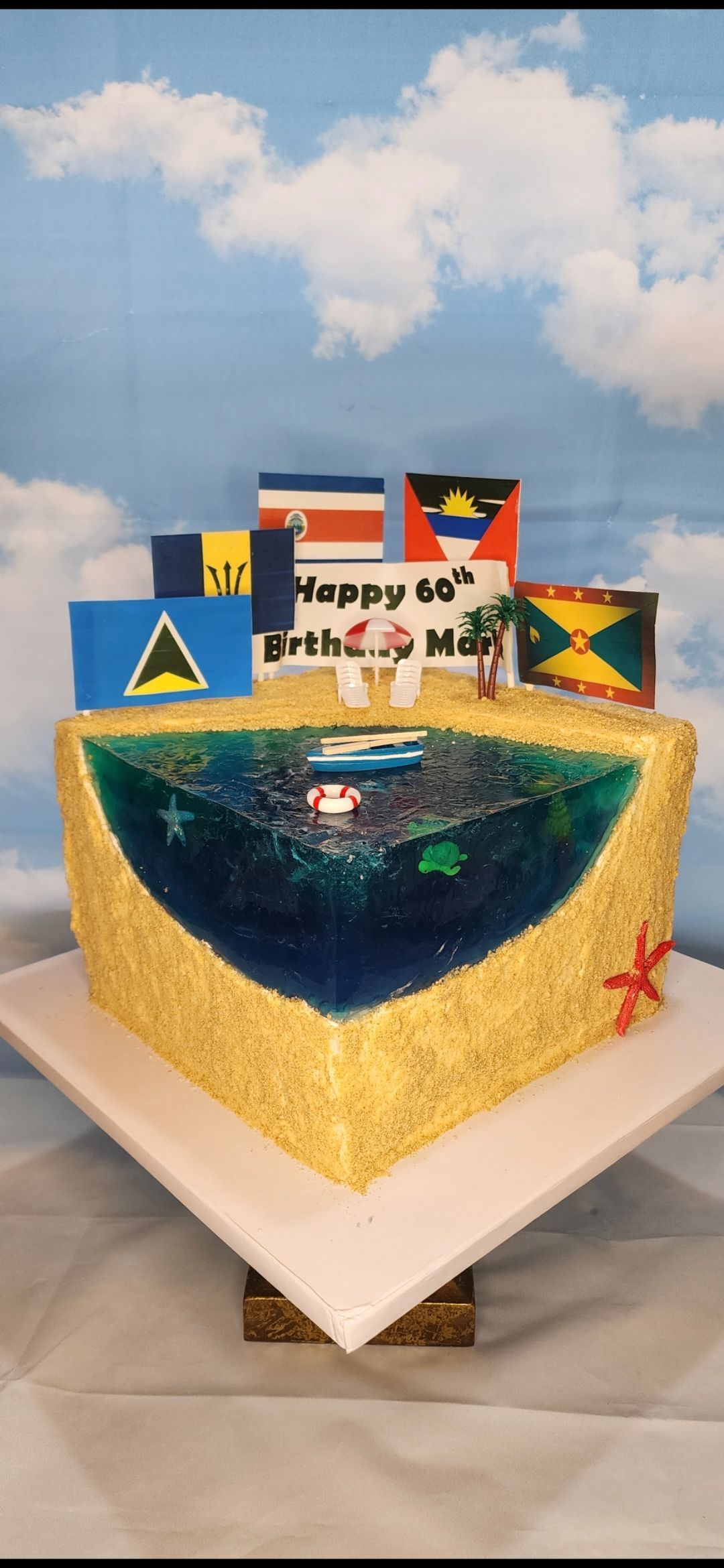 A cake that looks like a beach with flags on it