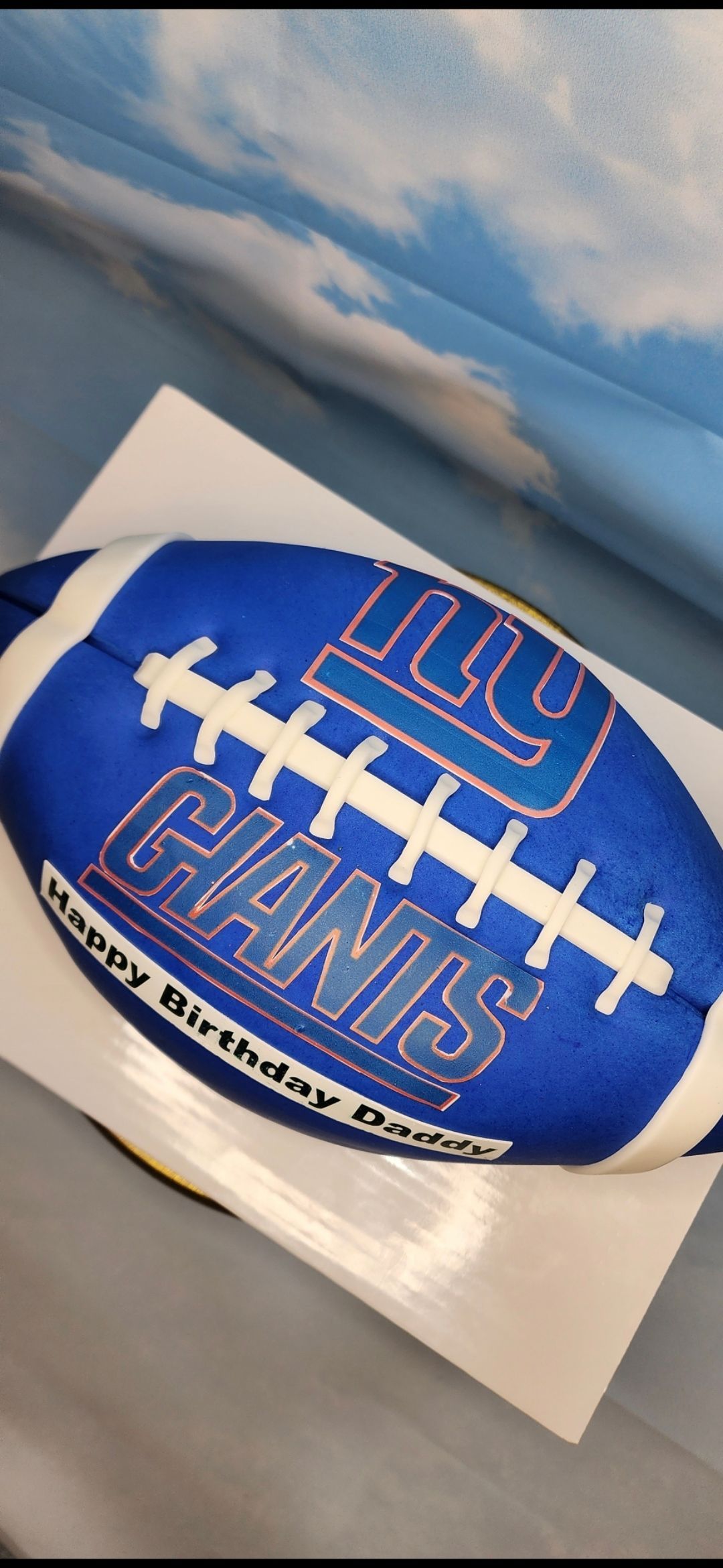 A birthday cake in the shape of a football for a new york giants fan.
