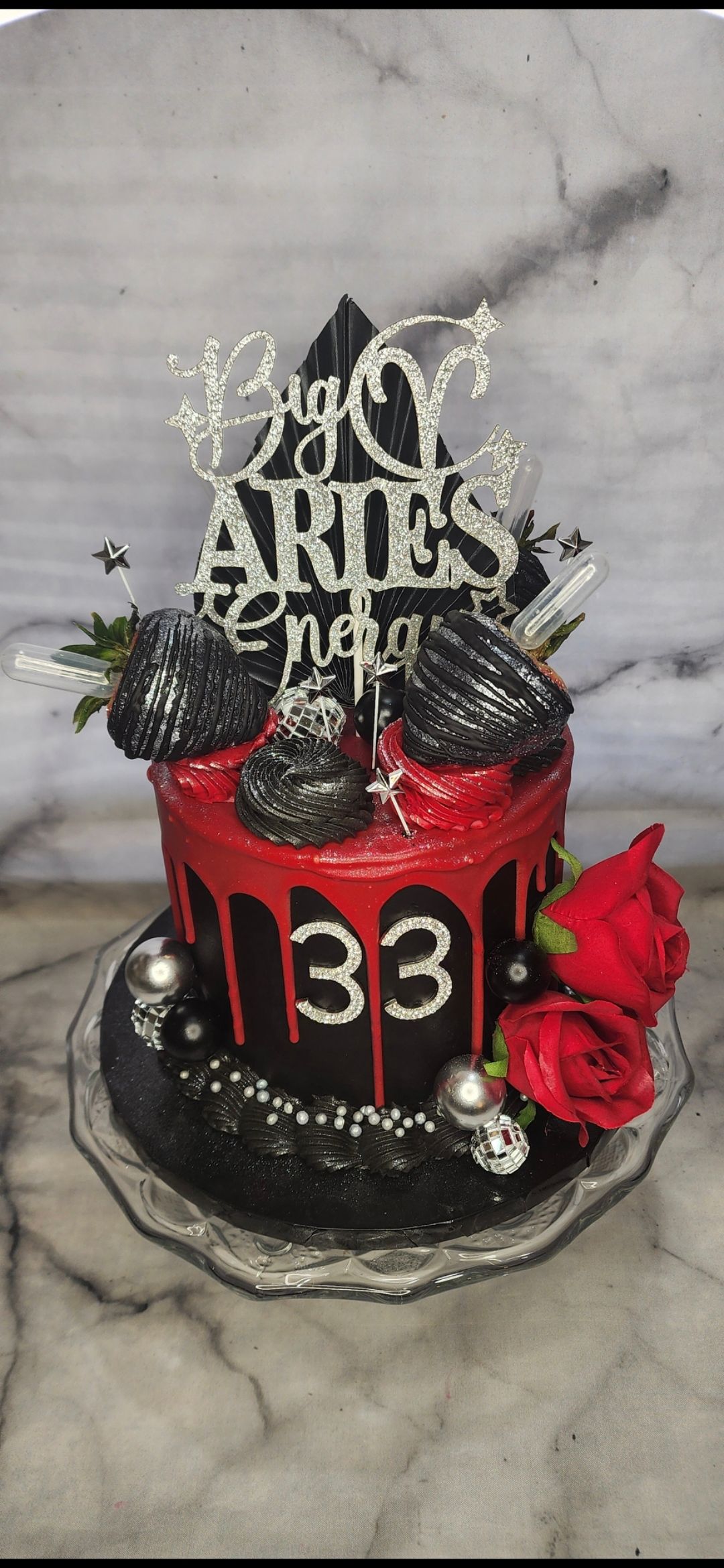 A black and red birthday cake with a topper on top of it.