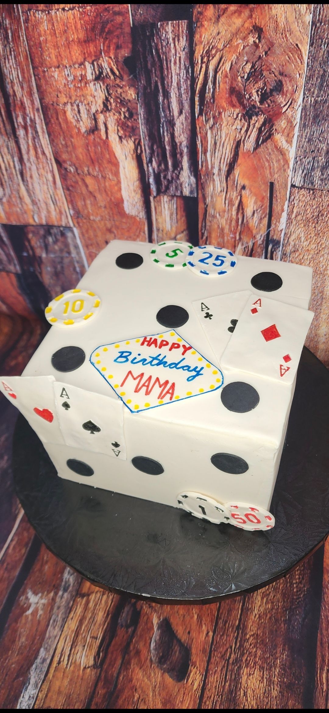 A birthday cake in the shape of a dice with playing cards on it.