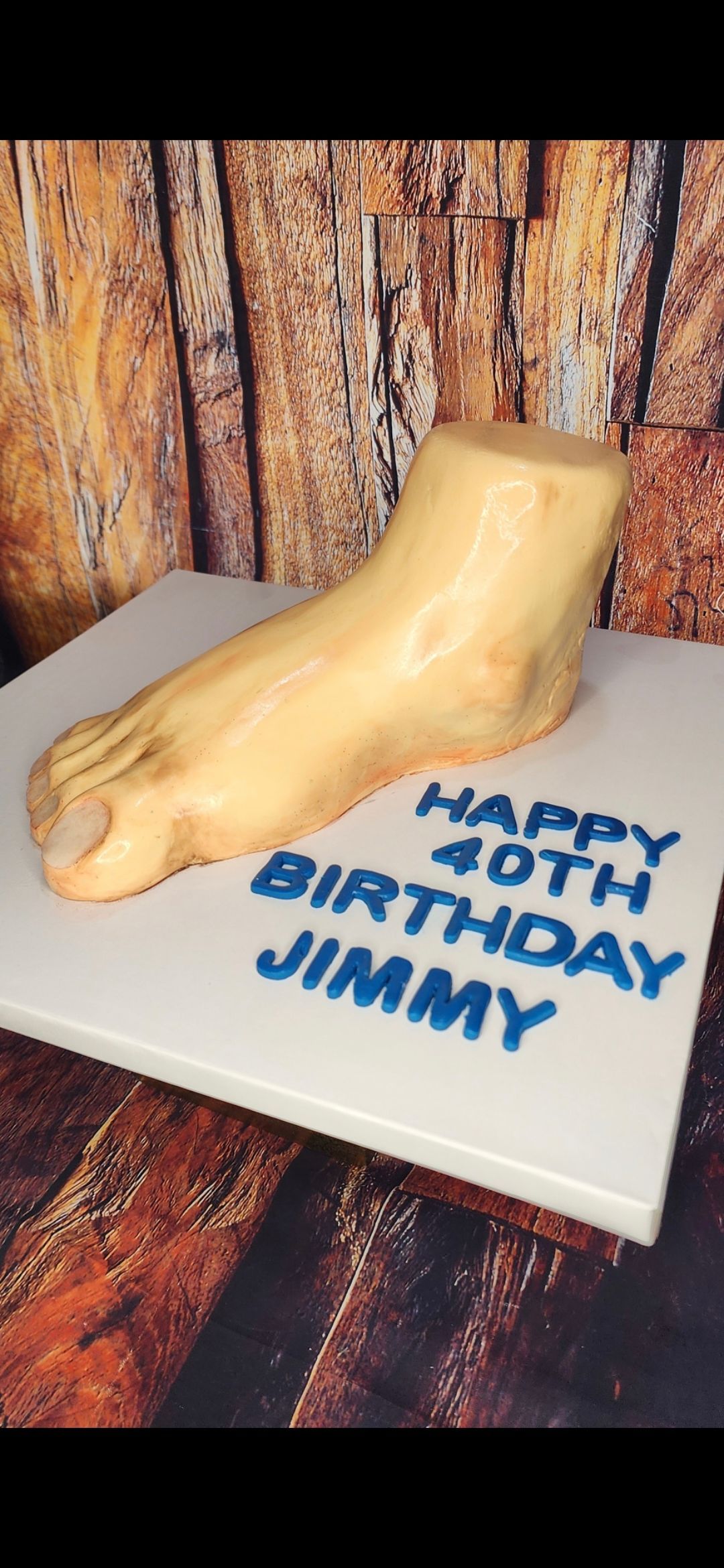 A cake with a foot on it that says happy 40th birthday jimmy