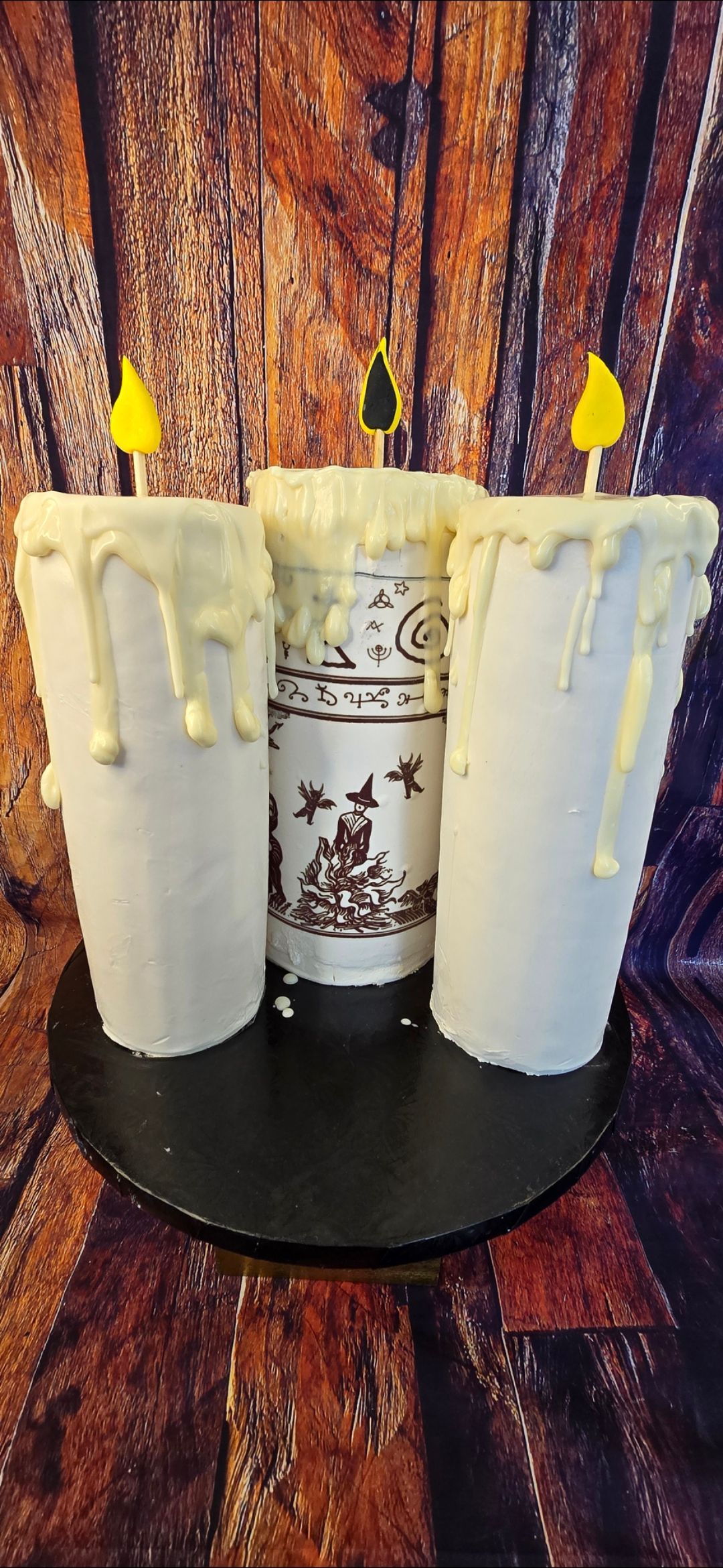 Three candles are sitting on top of a black plate on a table.