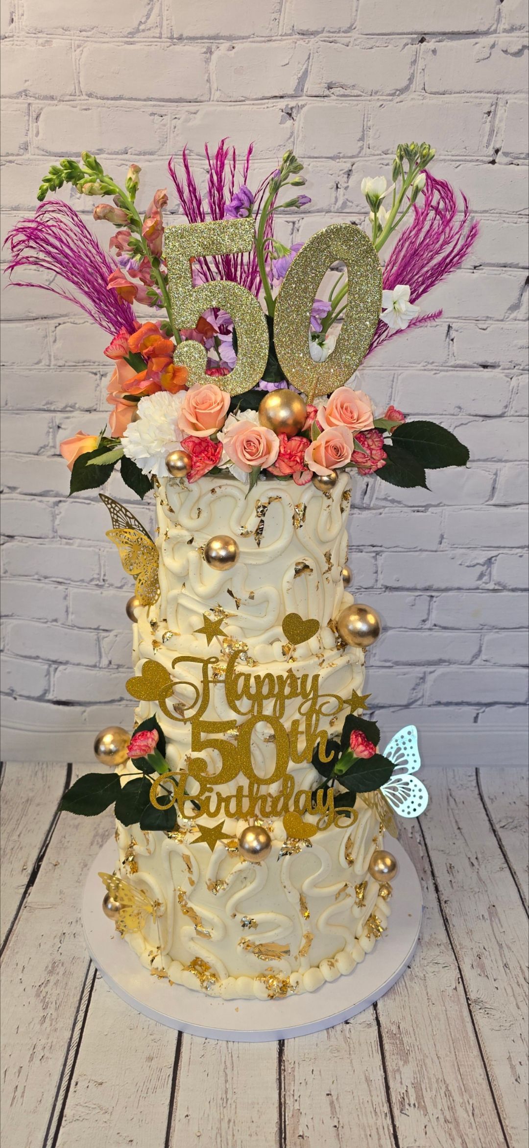 A cake with flowers and butterflies on top of it is on a table.