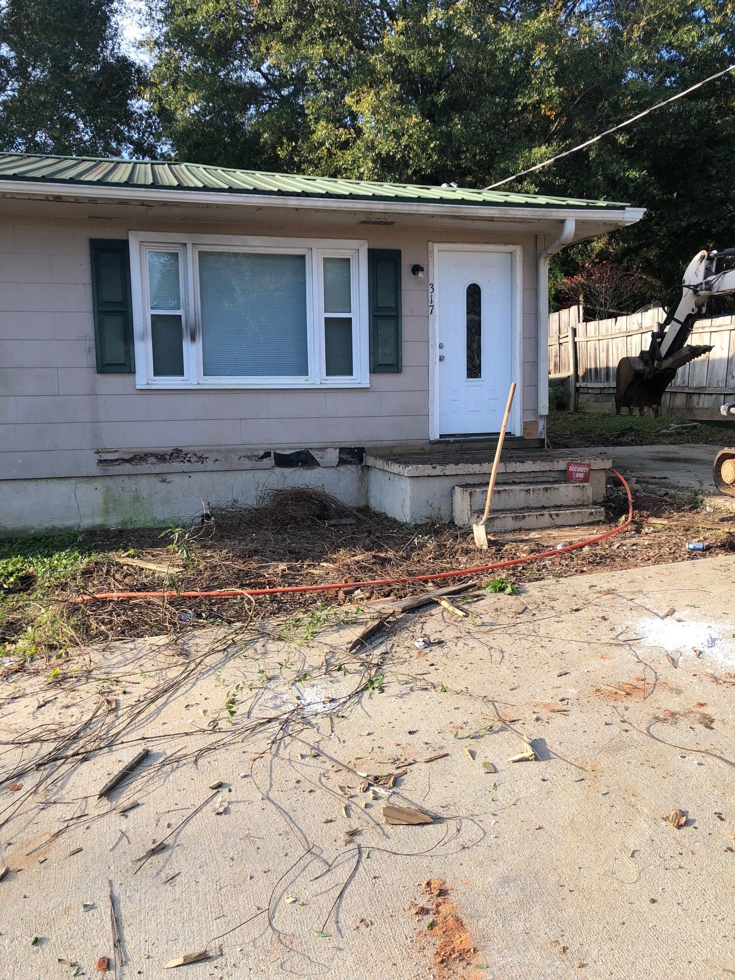 a house with a green roof and a white door is sitting on top of a dirt field .