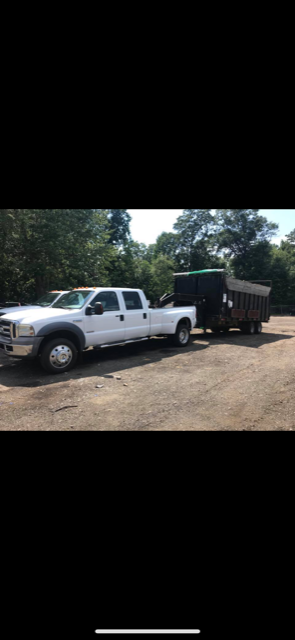 a white truck is towing a dumpster in a parking lot .
