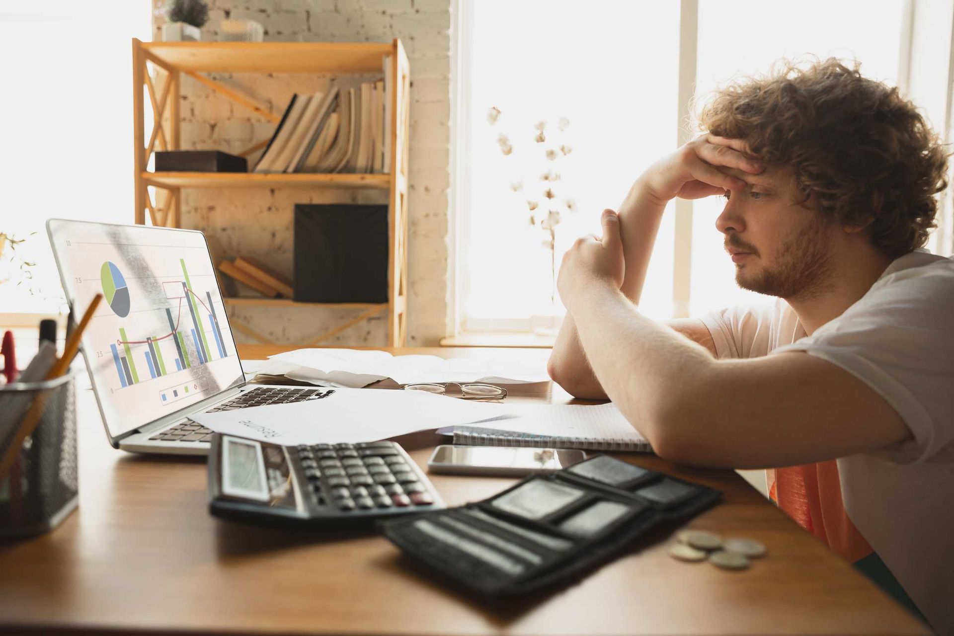 A man is sitting at a desk with a laptop and a calculator.