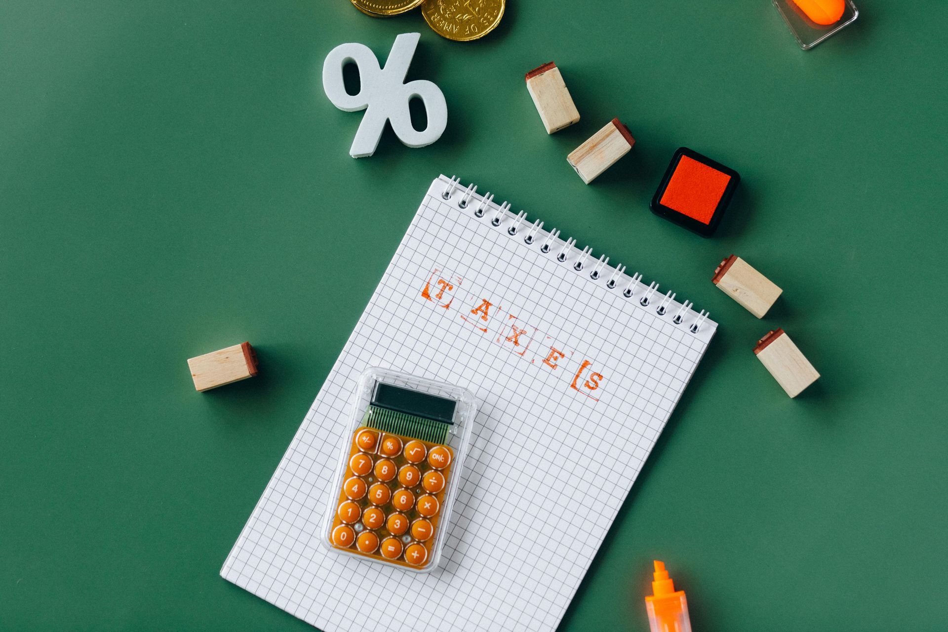 A notebook with a calculator and coins on a green table.