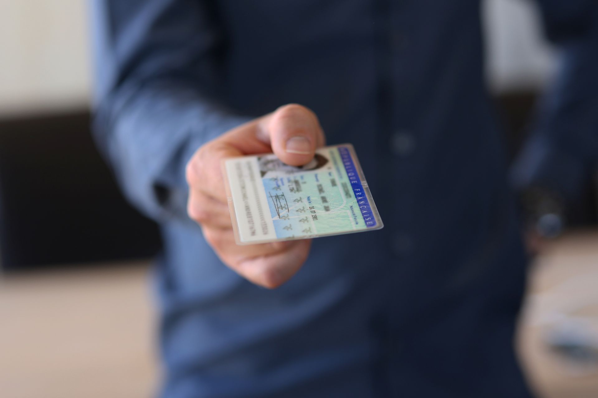 A man in a blue shirt is holding a drivers license