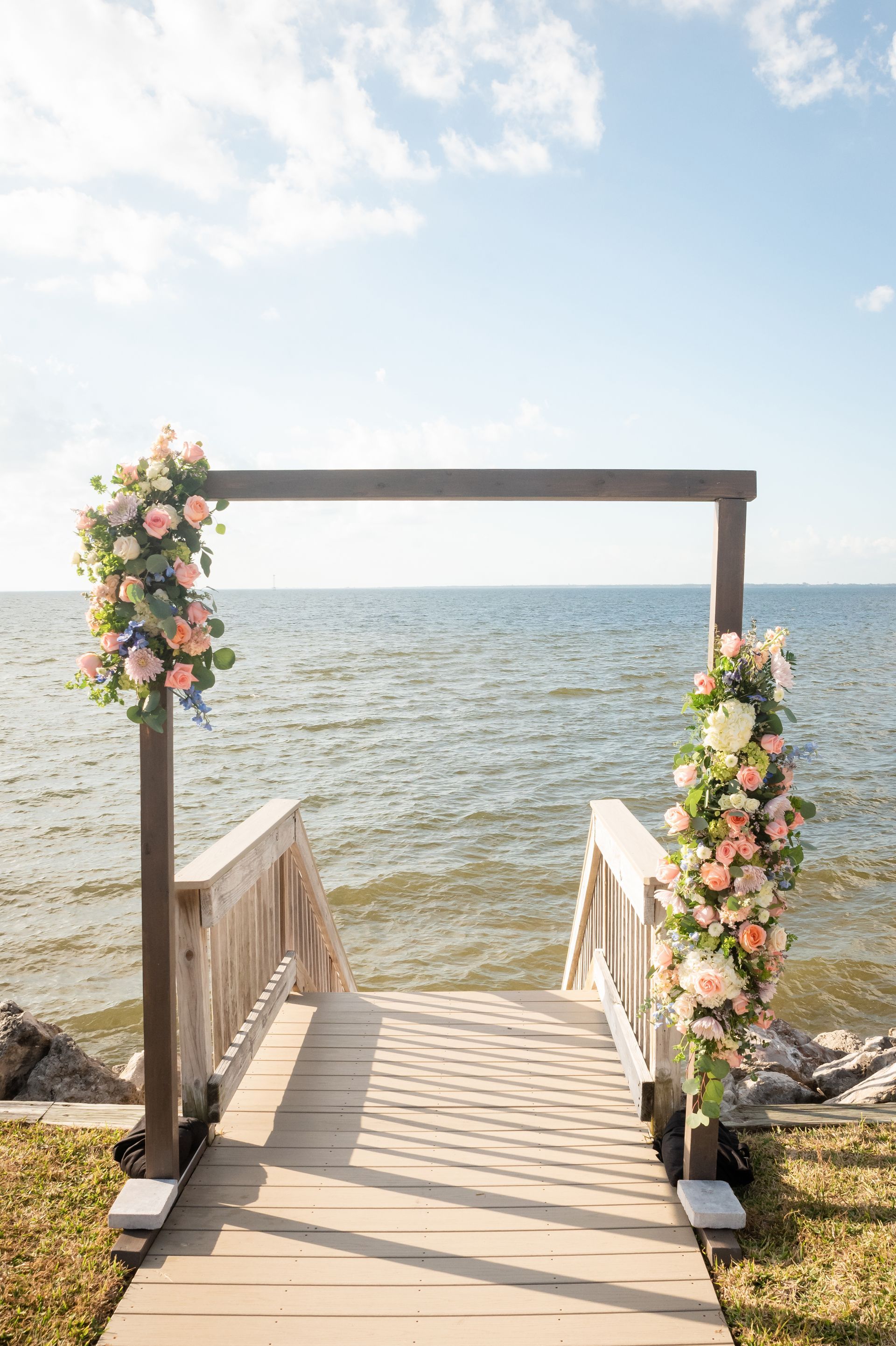 A wooden dock decorated with flowers is leading to the ocean.
