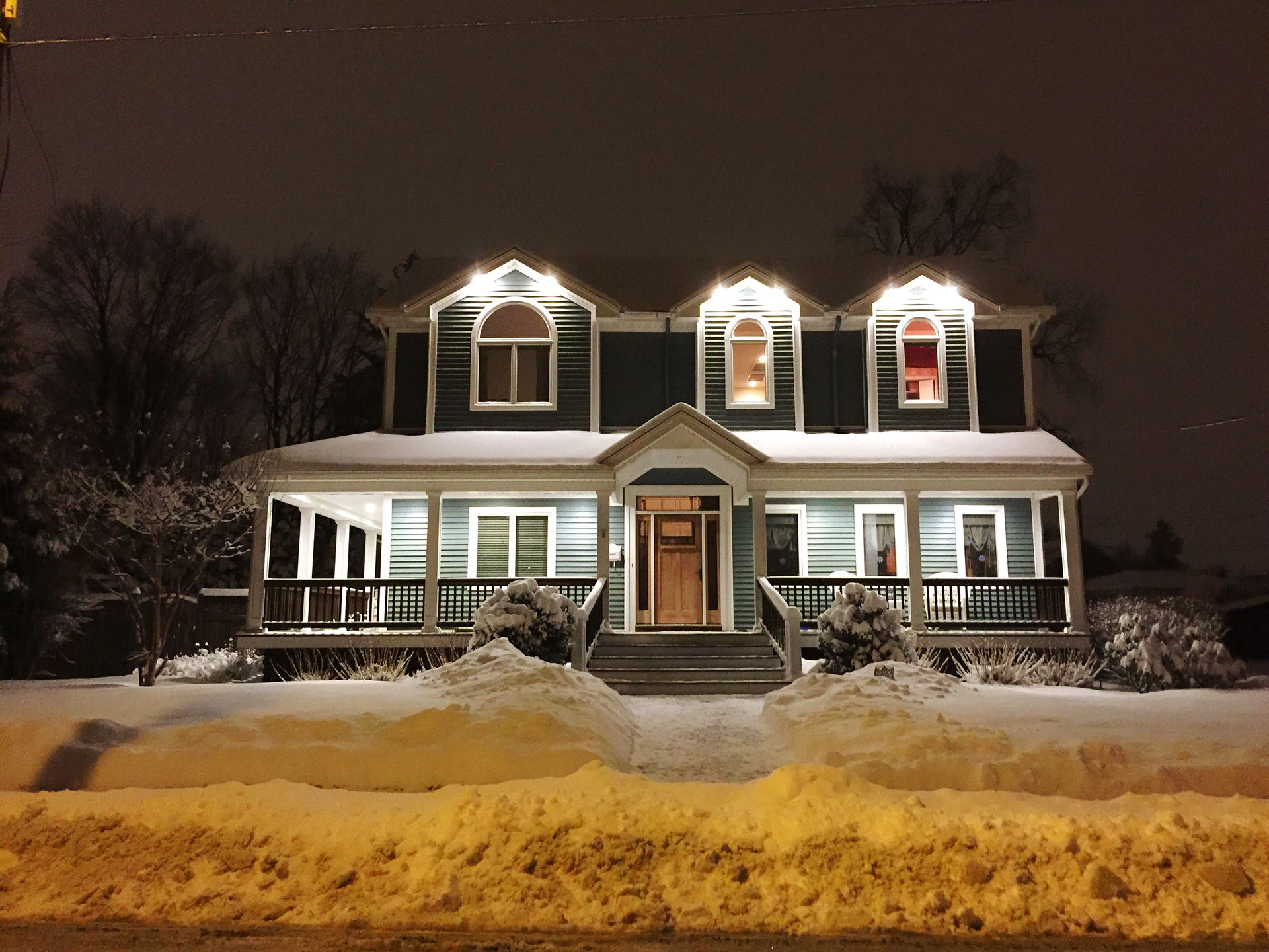 A house is lit up at night with snow on the ground