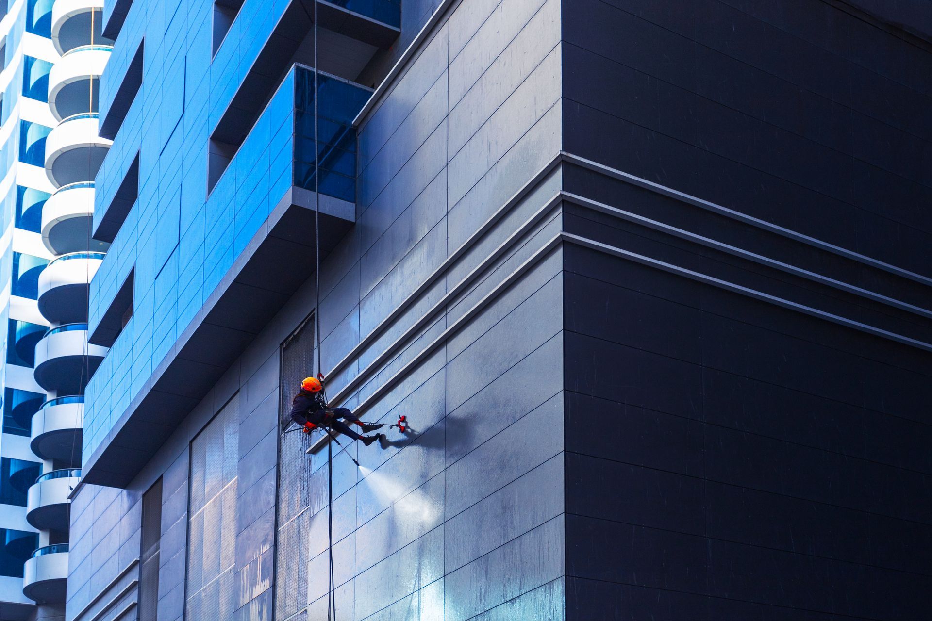 A man is spraying water on the side of a building.