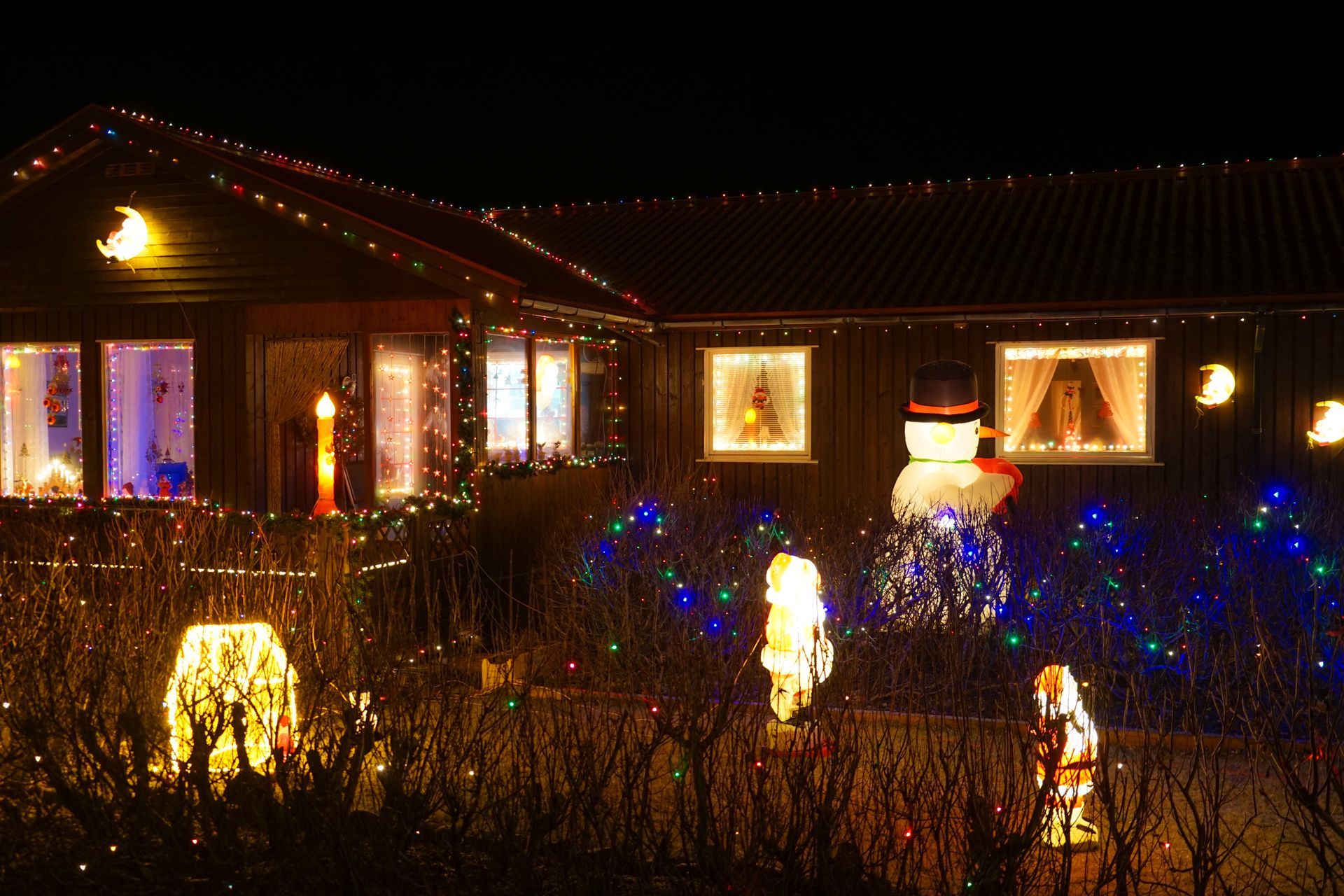 A house is decorated with christmas lights and a snowman