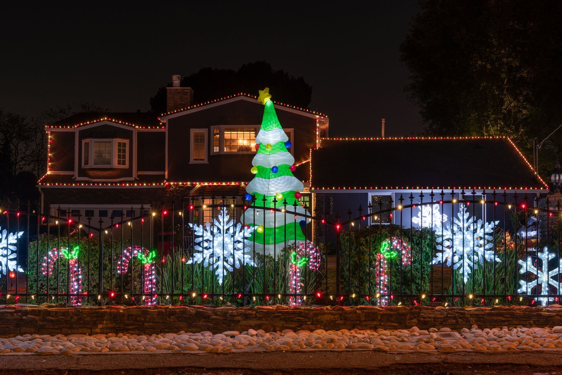 A house is decorated with christmas lights and a large inflatable christmas tree.