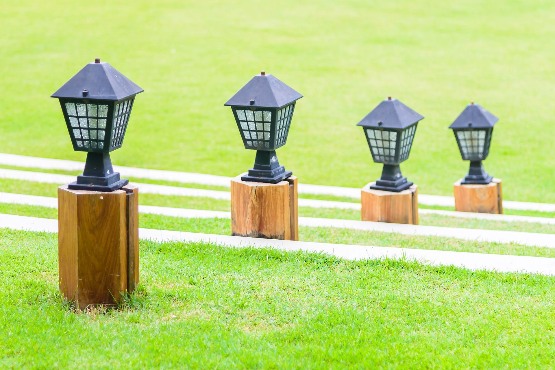 A row of lanterns sitting on wooden poles in a park.