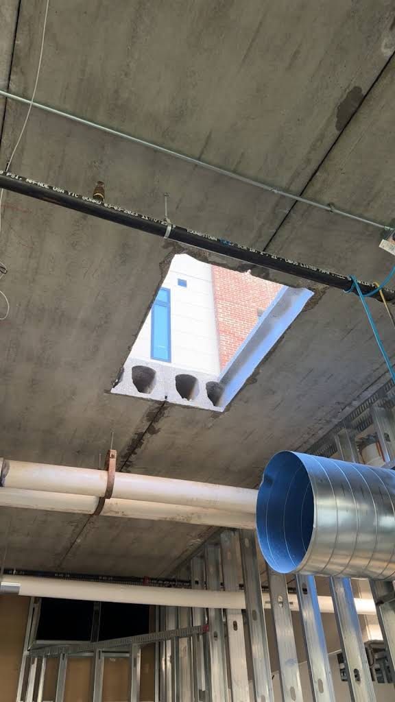 Concrete ceiling with a rectangular opening, revealing the sky and a building. Construction site interior.