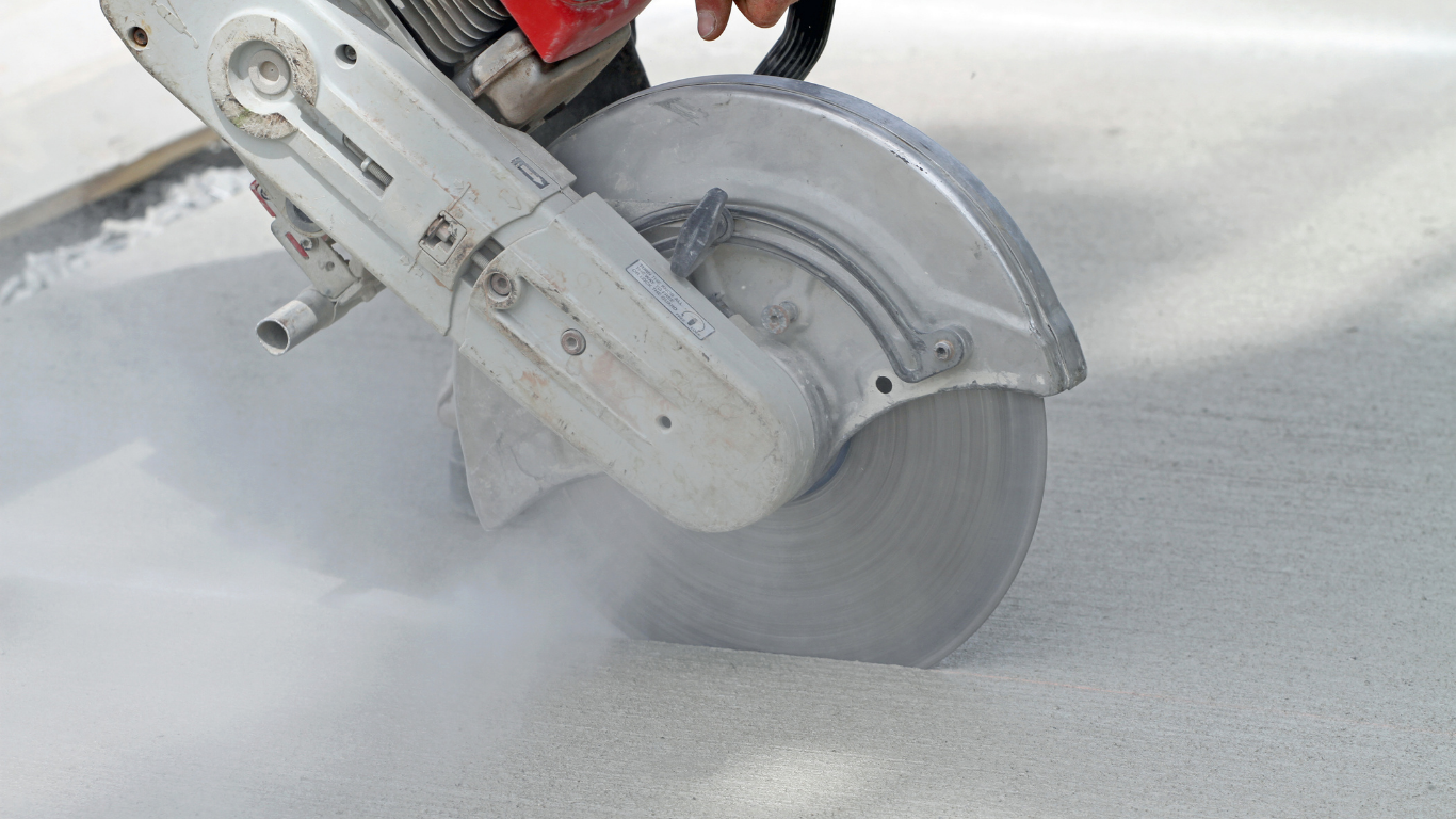 Circular saw cutting concrete, generating dust.