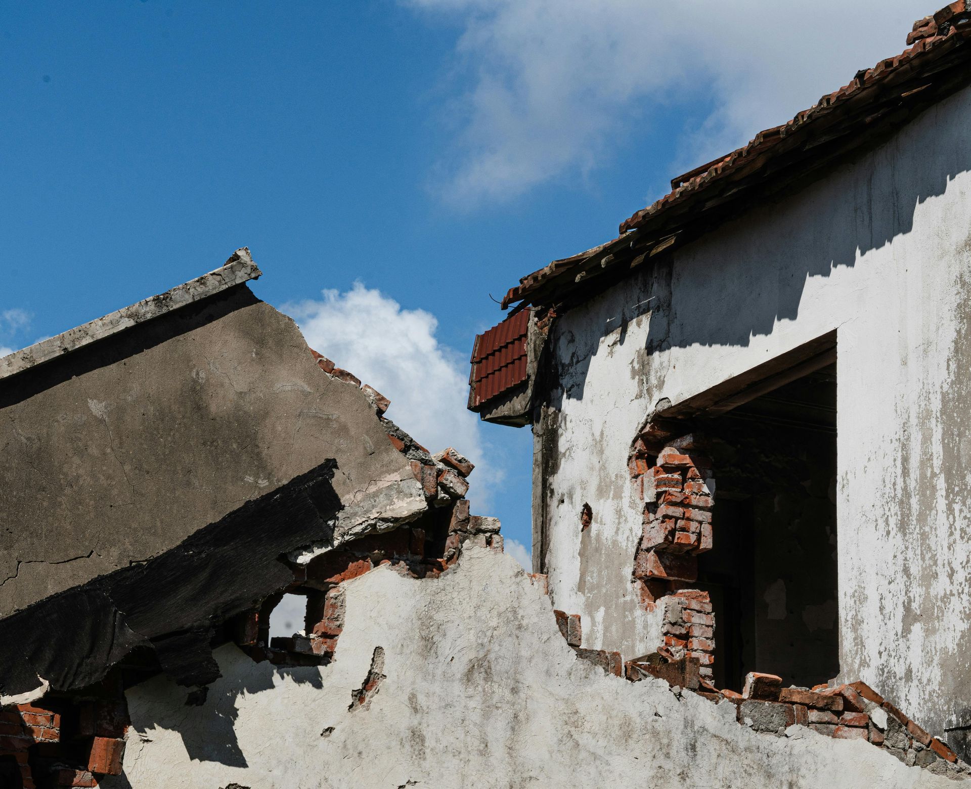 Damaged building with exposed brick against a blue sky.