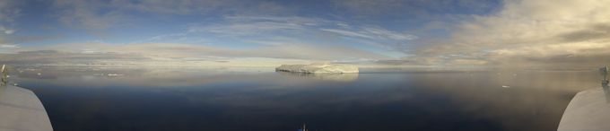 an iceberg is floating in front of a cruise ship.