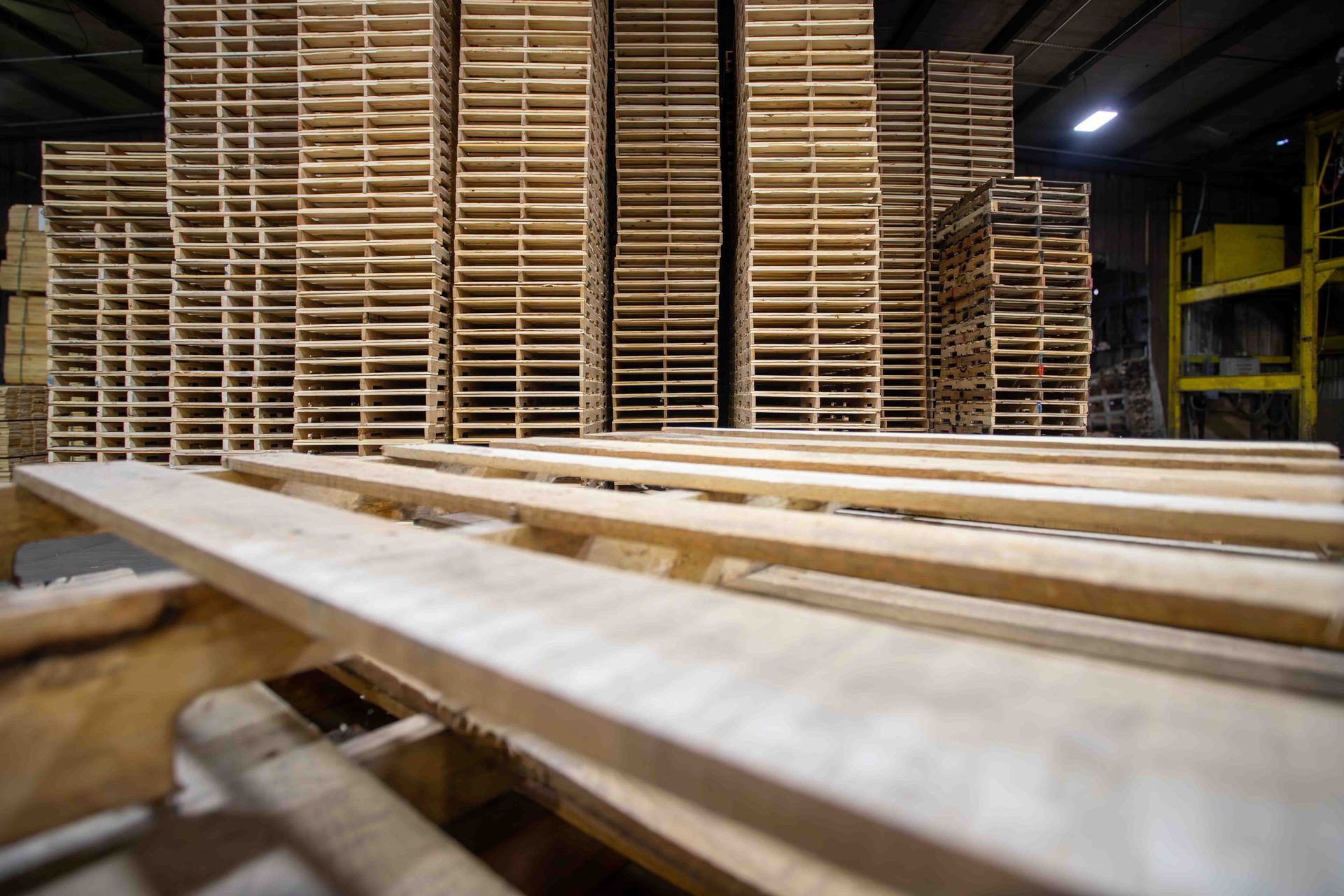 A warehouse filled with lots of wooden pallets stacked on top of each other.