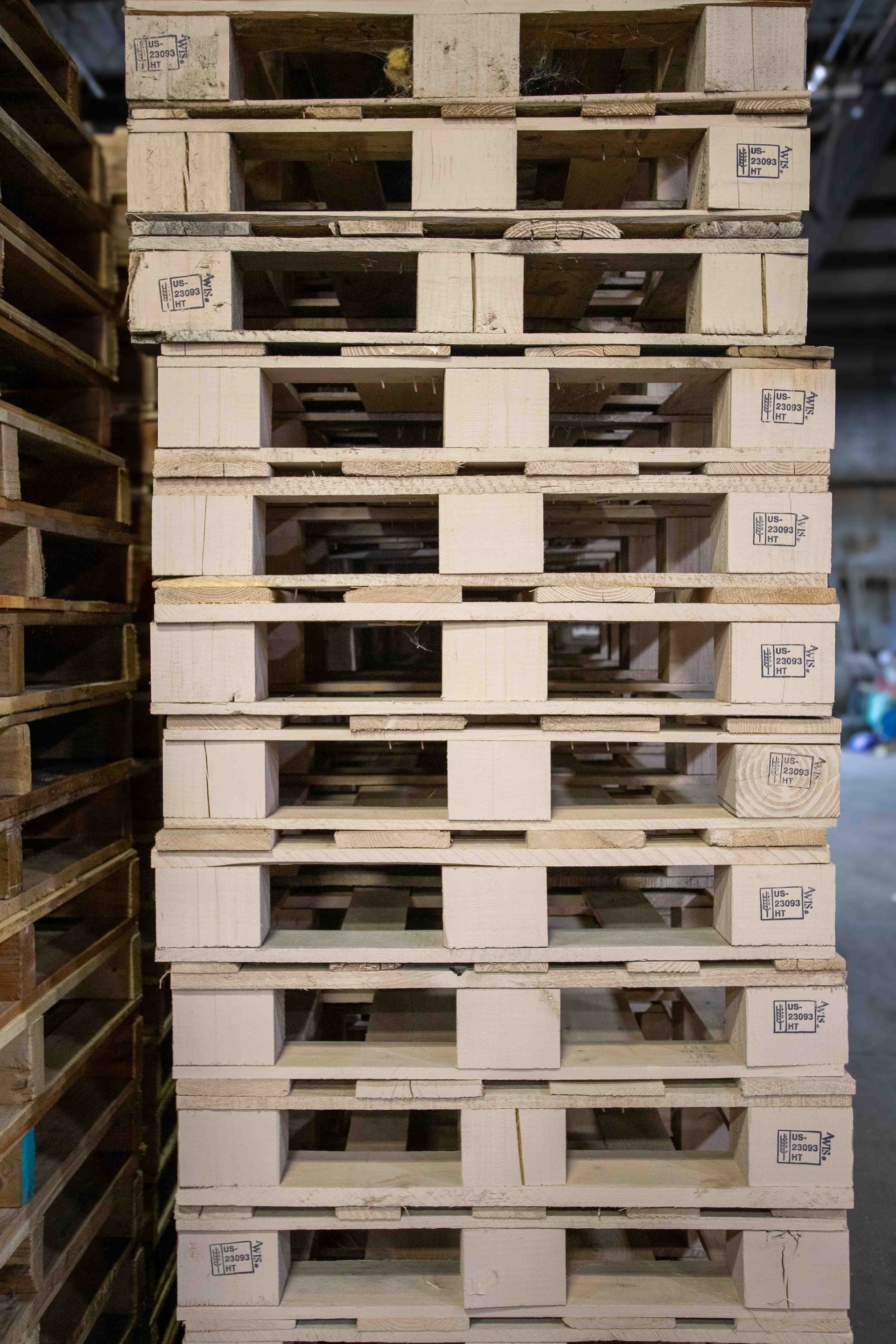 A stack of wooden pallets are stacked on top of each other in a warehouse.