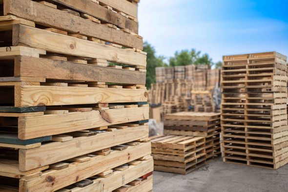 A bunch of wooden pallets are stacked on top of each other in a yard.