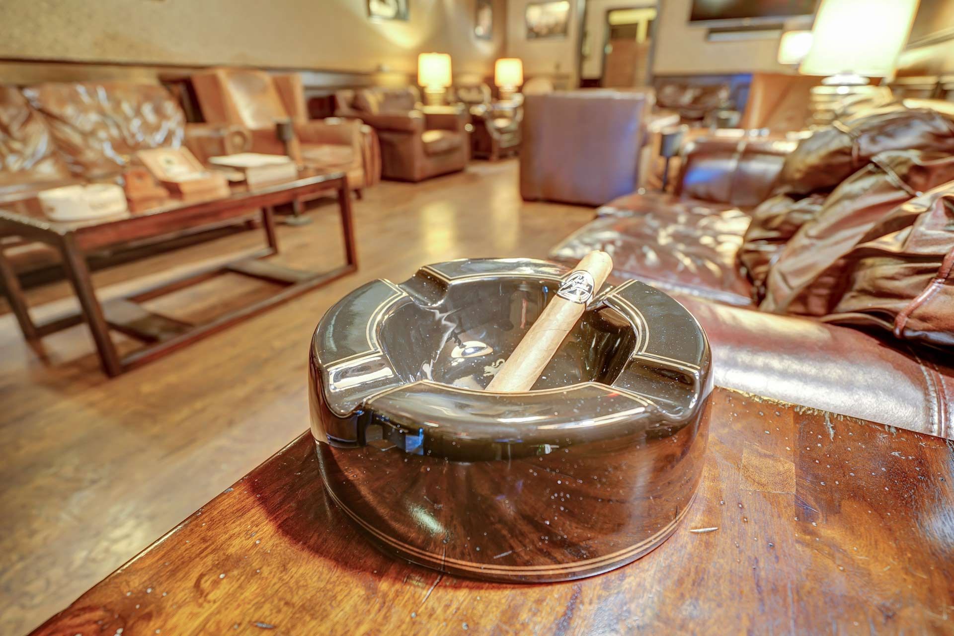 Cigar nestled in the groove of a simple, circular ashtray
