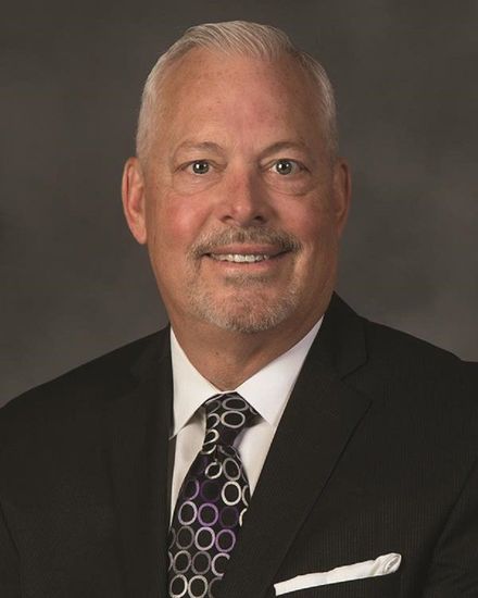 A man in a suit and tie is smiling for the camera.