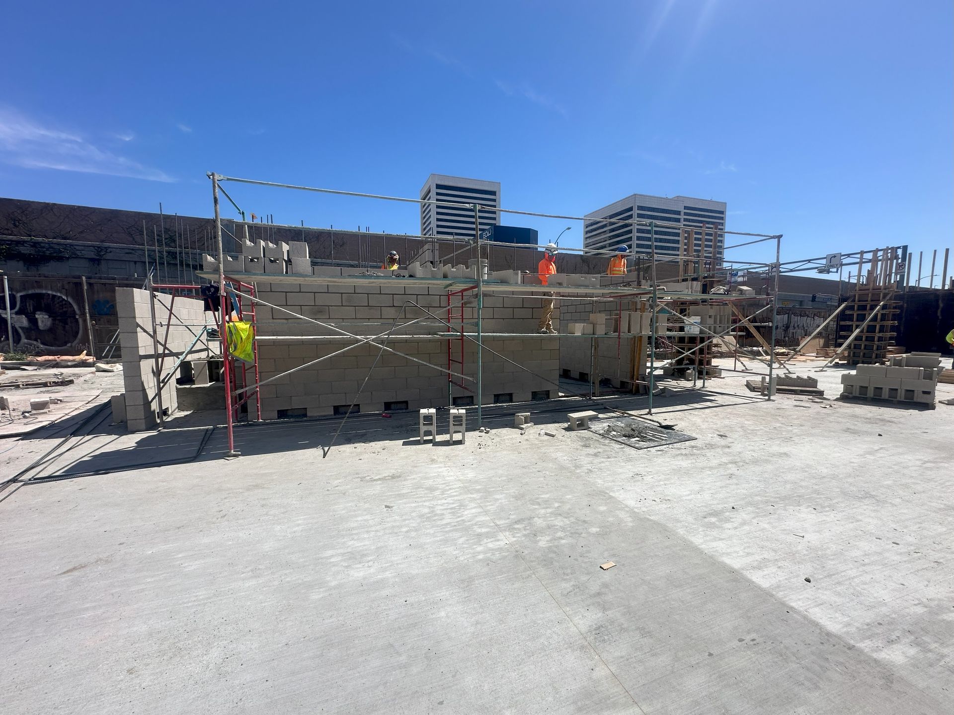 Construction site with scaffolding and concrete blocks under a bright blue sky.