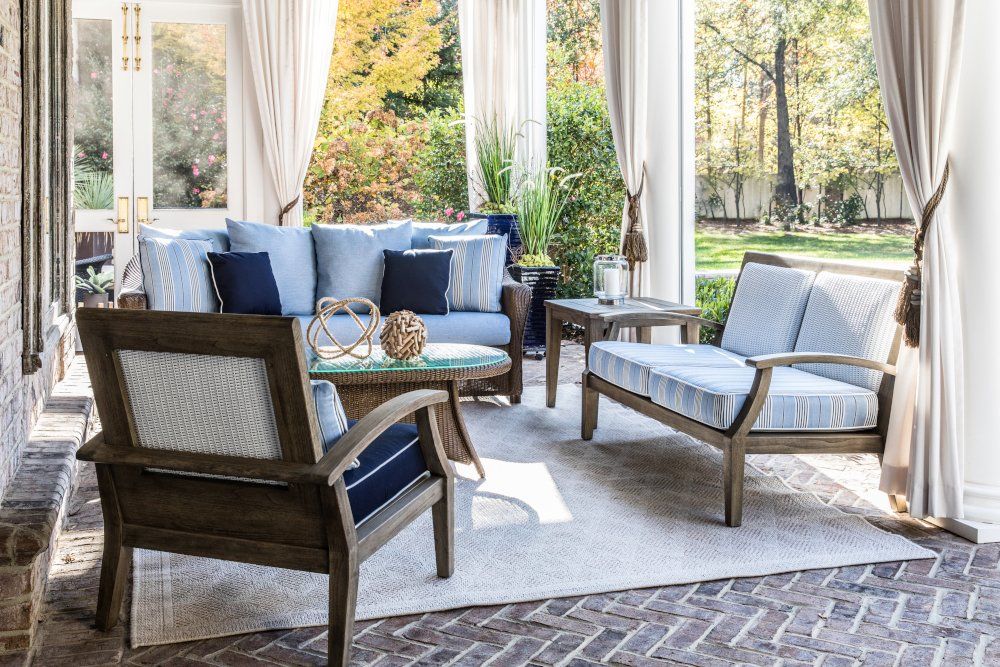 Outdoor seating area with blue cushions, white rug, and fall foliage.