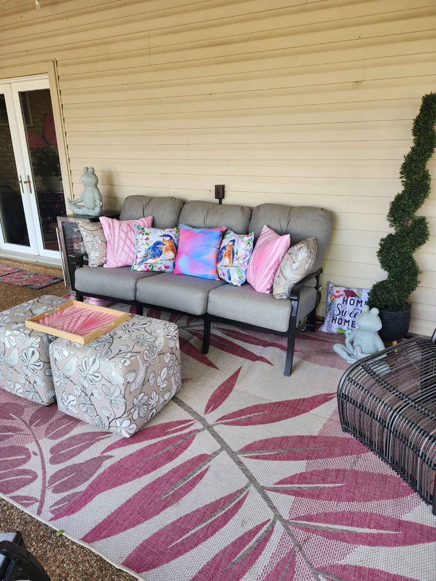 Outdoor patio with sofa, patterned rug, and floral pillows.
