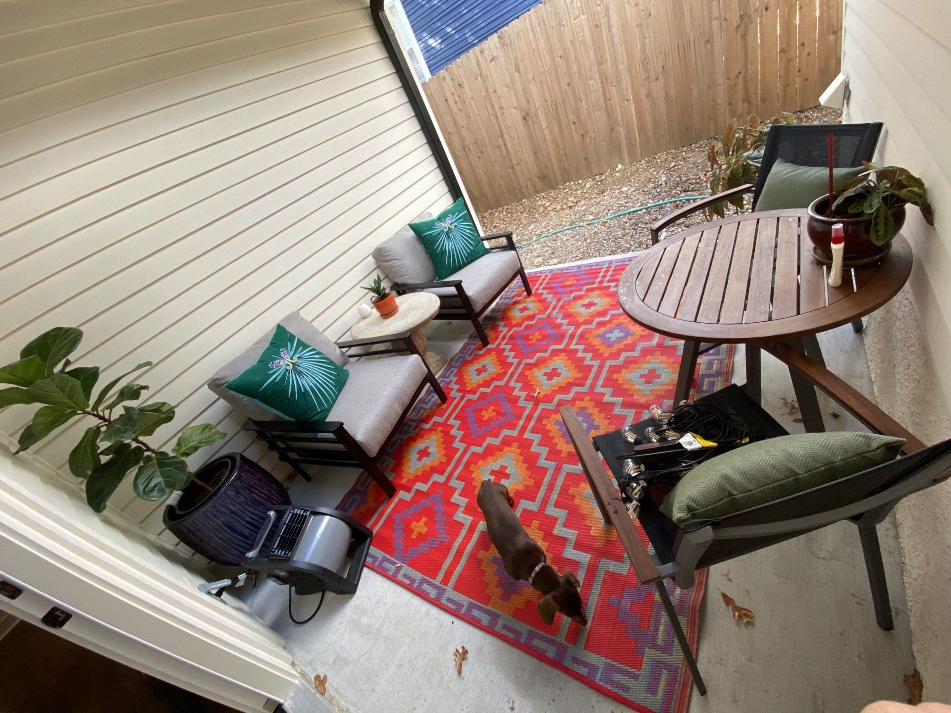 Patio with furniture, patterned rug, and plants. Bright red, orange, and teal colors.