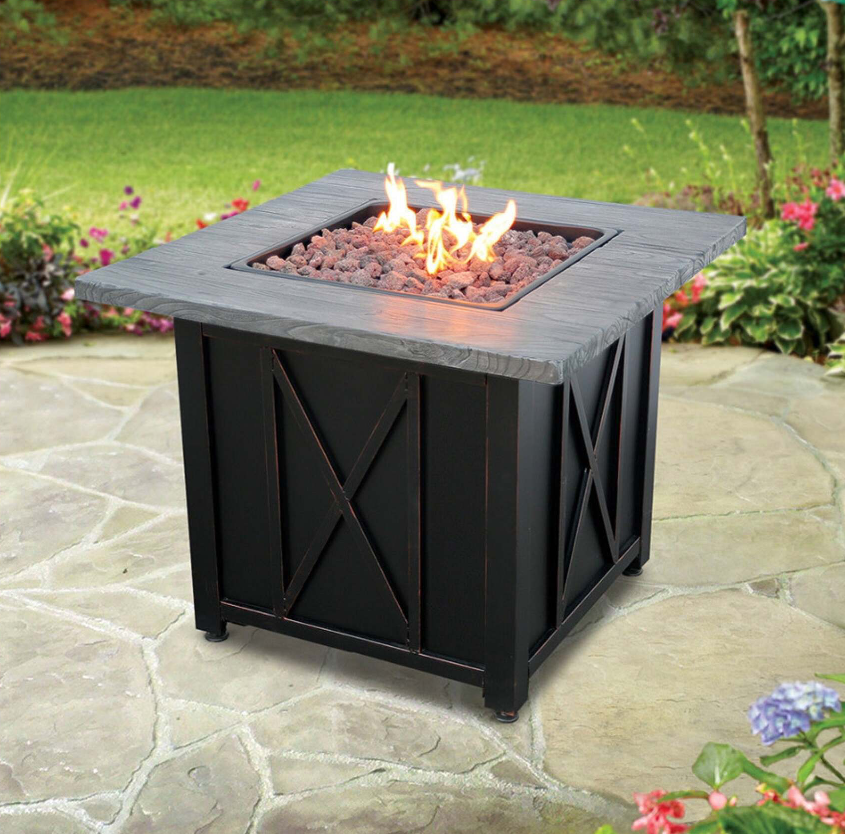 Black outdoor fire pit with gray top and burning flames.