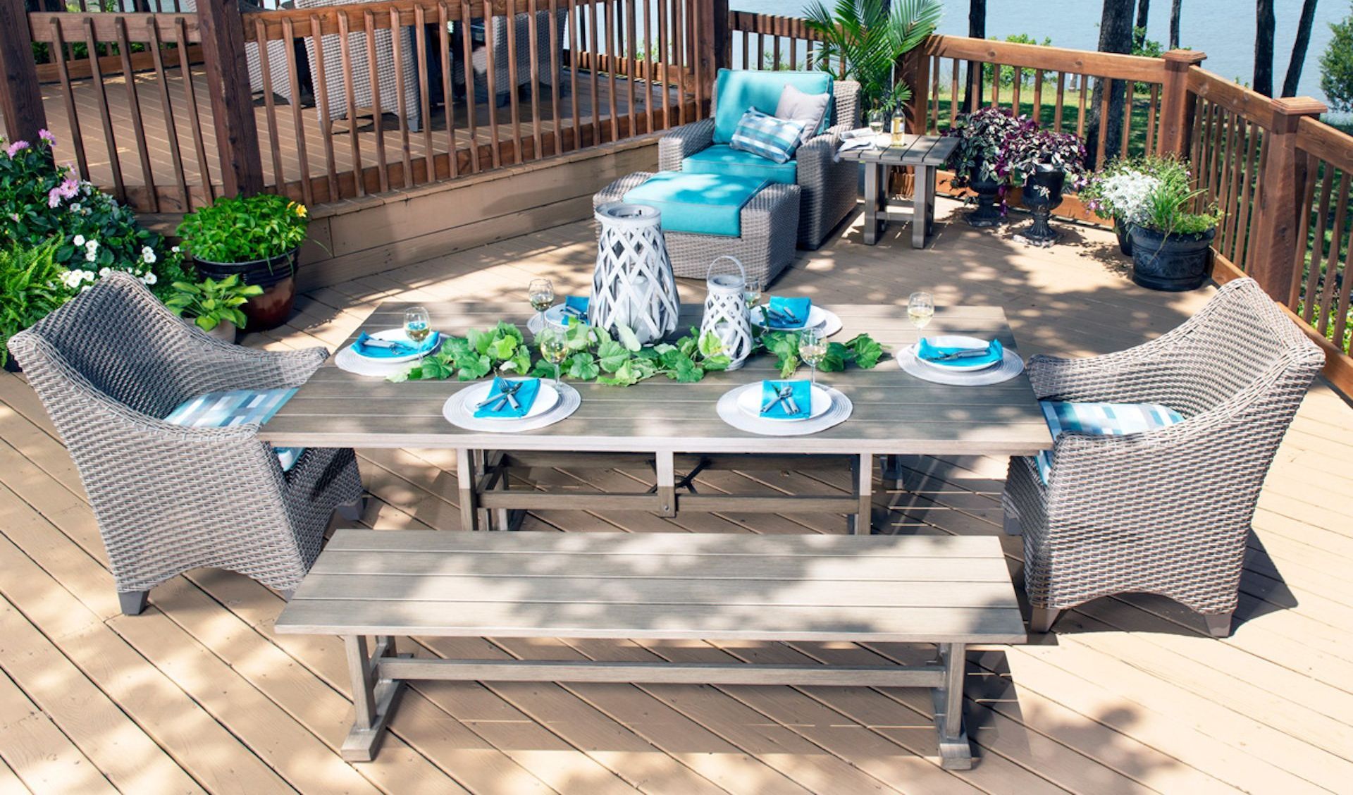Outdoor deck with dining table, wicker chairs, blue cushions, and decorative plants.