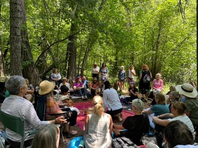 A group of people are sitting in a circle in the woods.