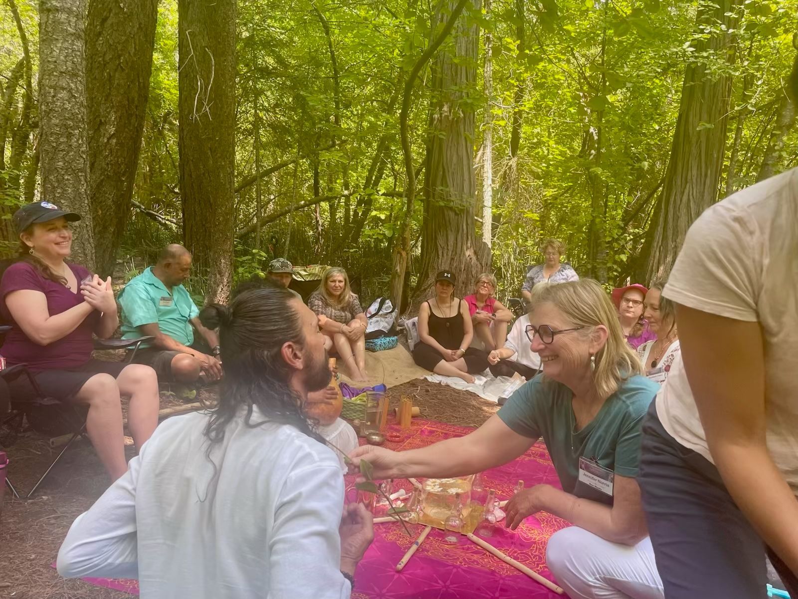 A group of people are sitting in a circle in the woods.